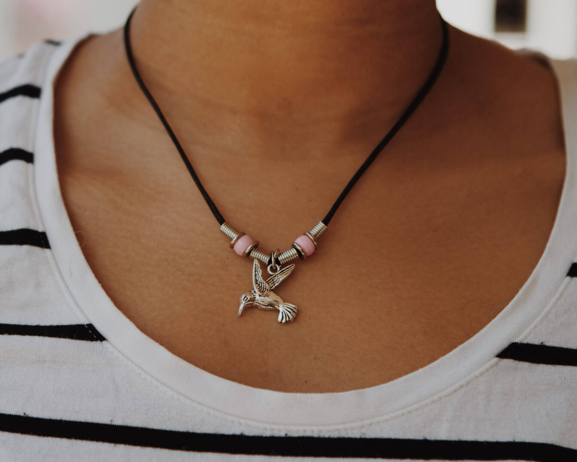 Close-up of a necklace with charms worn on a person's neck.